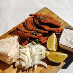 Aqashi with flatbread, onion, lemon and sauce on a board