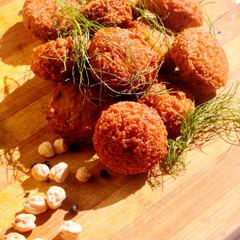 Freshly fried falafel with fennel fronds and dried chickpeas on a wooden board