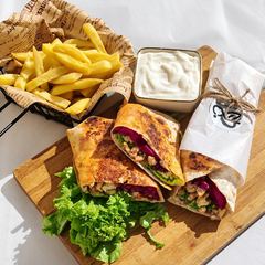 Chicken shawarma wraps with chips, lettuce and white sauce on a board