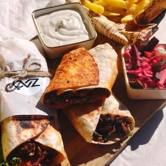 Beef shawarma wraps with chips, white sauce and pickled vegetables on a board